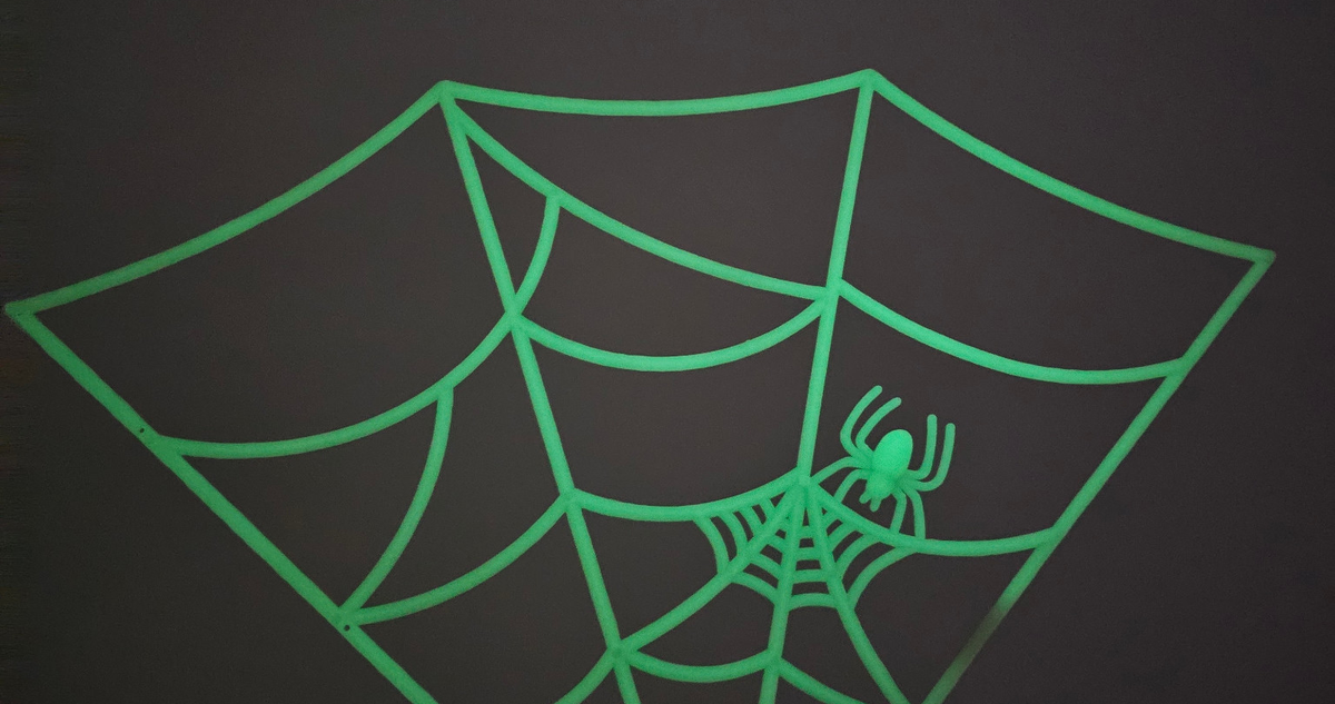 Actual glow close-up of one section of the four-section spider web; cropped original photo, brightness unchanged