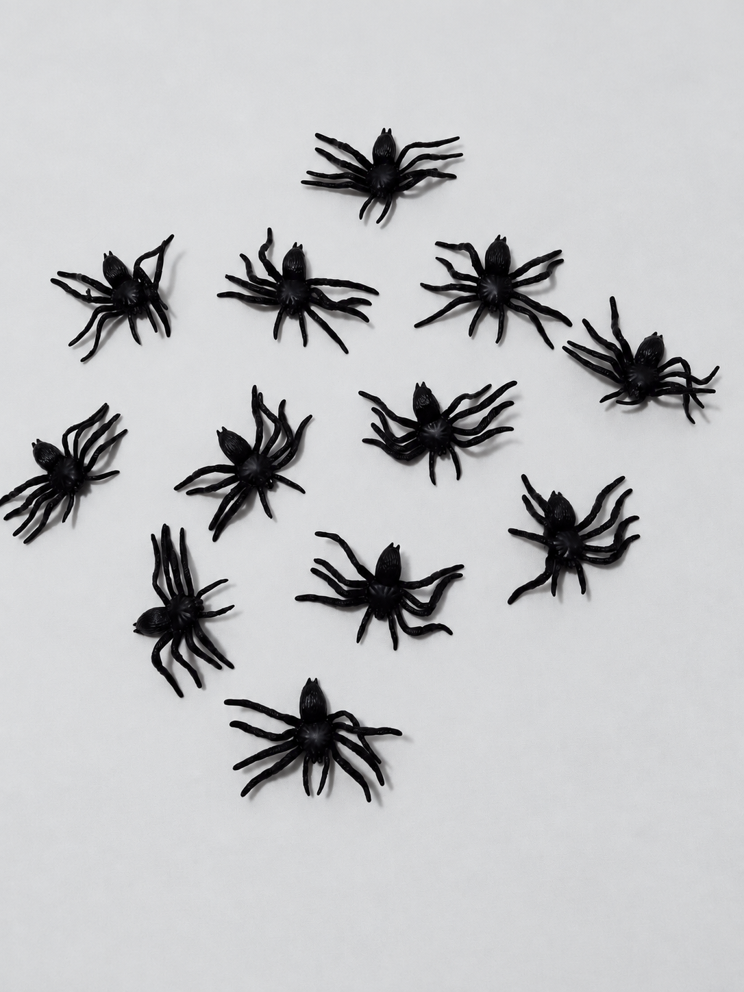 Retouched actual stock photo of twelve black toy spiders; mesh bag not shown