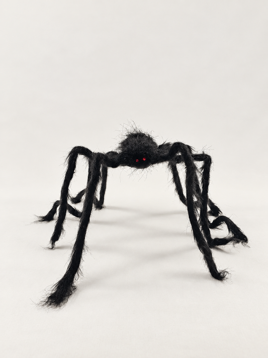 Black bendable spider with fuzzy legs and red eyes, photographed from actual stock; background and lighting retouched