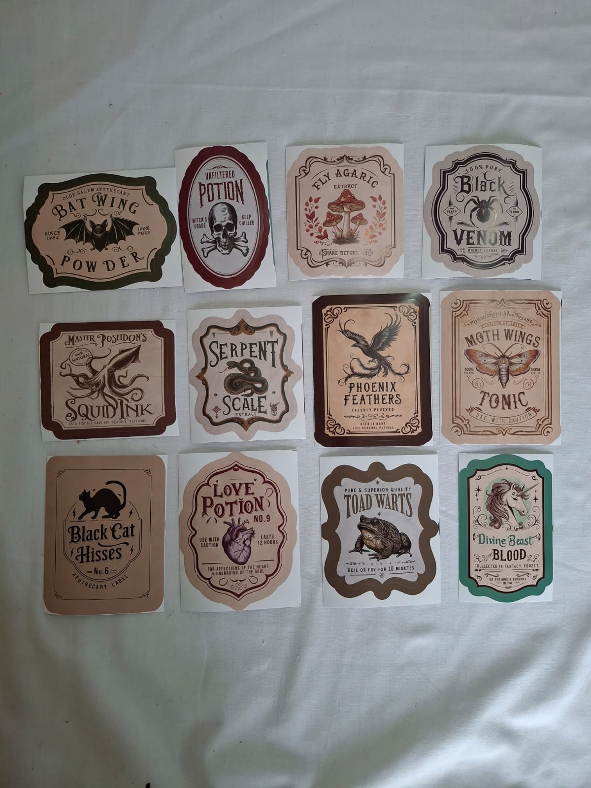 Bottled Mischief unaltered product photograph showing all 12 potion bottle label designs in four columns and three rows; labels only, bottles not included.